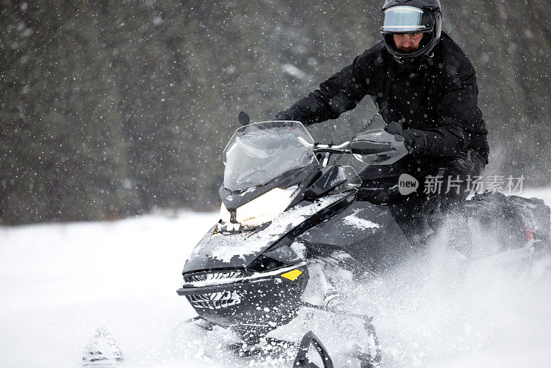 一名男子开着雪地摩托在粉状积雪中超速行驶