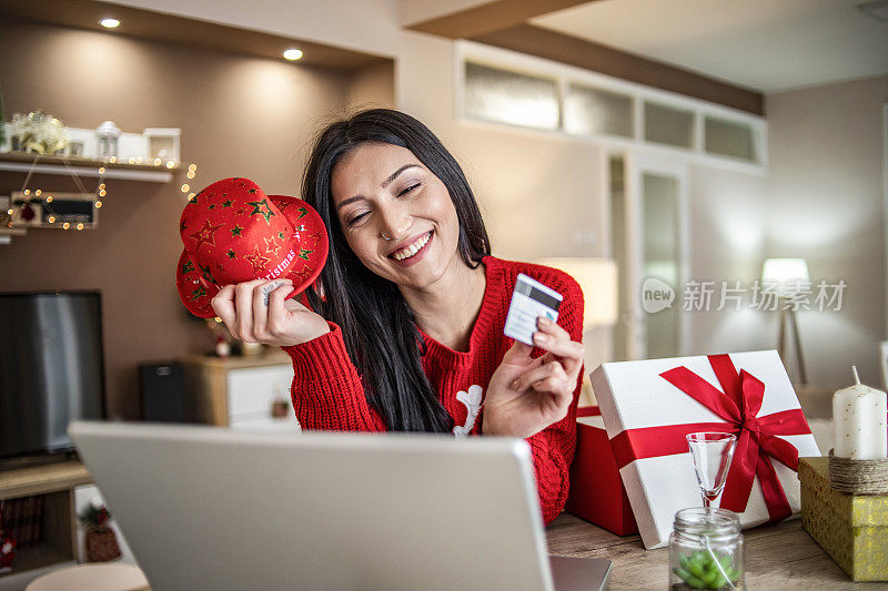 女人用信用卡在家里买新年的礼物-圣诞购物-一个年轻女人在网上买礼物的特写