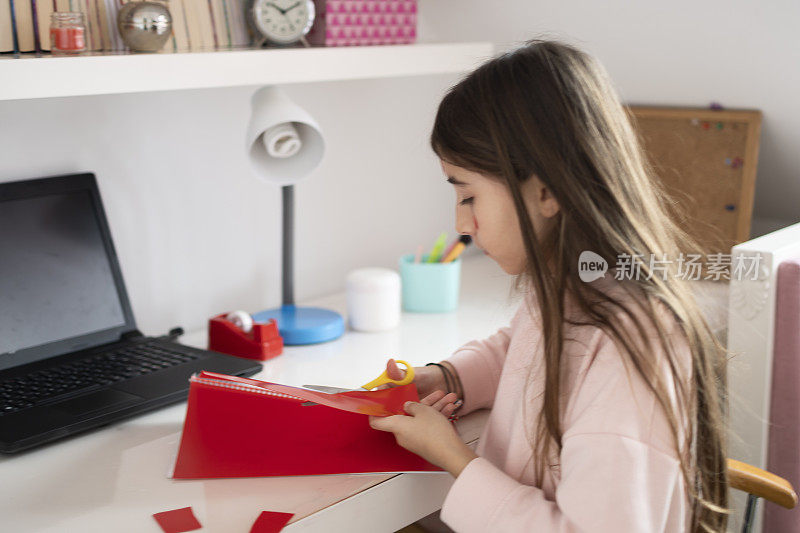 小女孩在剪塑料笔记本