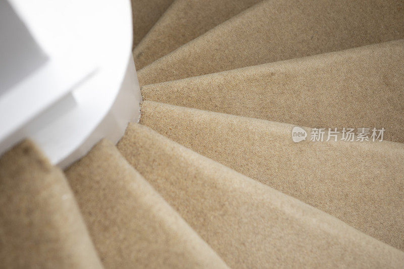 俯视着螺旋形的楼梯，上面铺着米色的地毯
