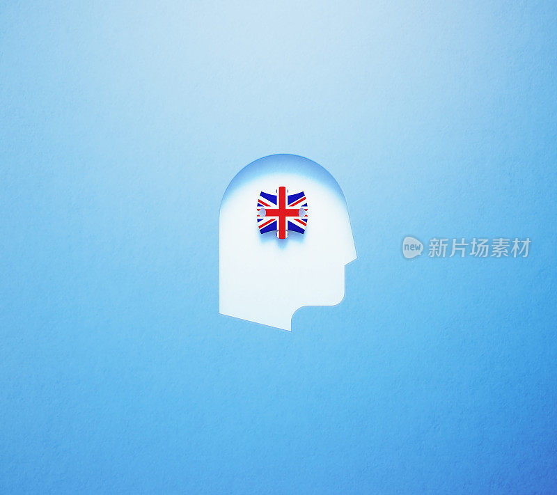 英语学习和说概念-拼图块纹理与英国国旗坐在里面在蓝色的背景上剪出的人头形状