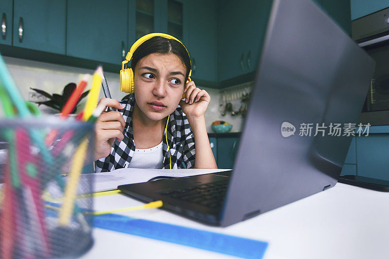 Тeenage女孩与耳机有问题的互联网连接在远程学习。