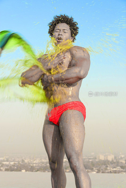 夏季泼彩色水-肖像运动非洲裔拉丁男性穿着红色泳衣男性比基尼泼彩色水液体