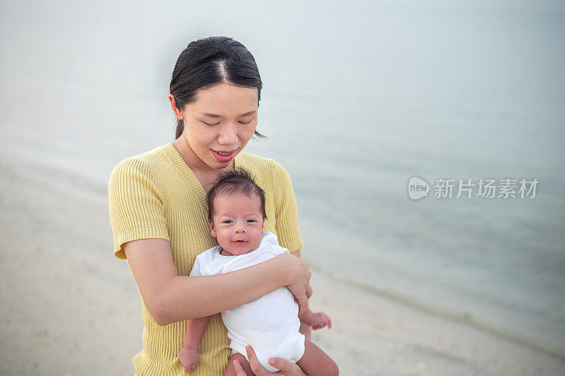 日落时分，母亲抱着刚出生的小男孩在海边