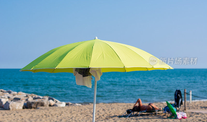 在海滩上，一把打开的黄色沙滩伞