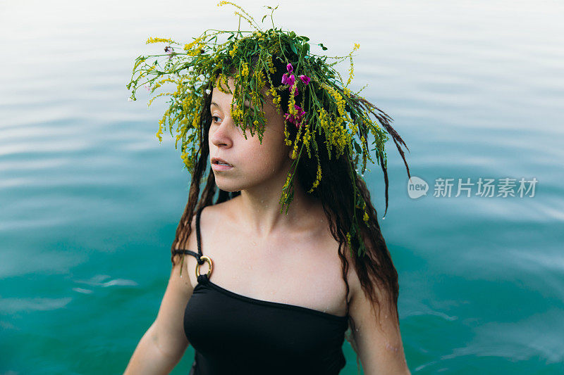 在夏季库帕拉夜，年轻女子戴着花环在湖中游泳
