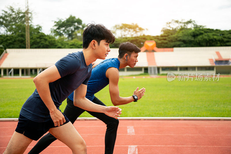 两名年轻的亚洲男子运动员在体育场的跑道上准备开始跑步和训练