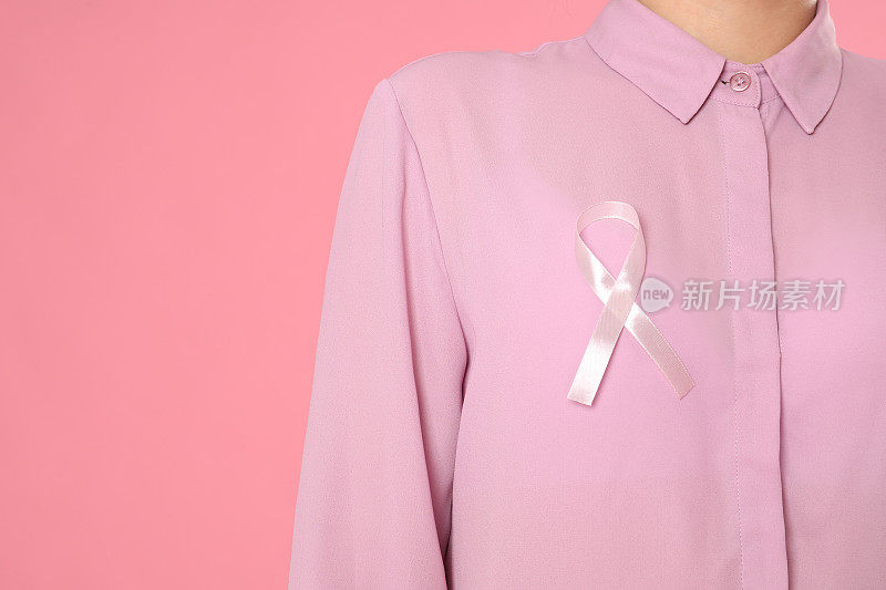 特写妇女与粉红色丝带的颜色背景，为文本的空间。乳腺癌意识