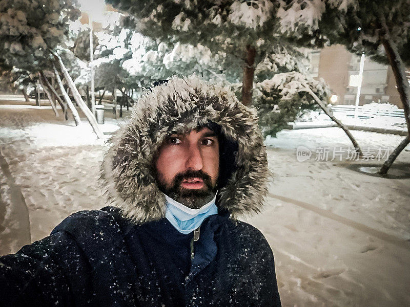 一名成年男子在城市的雪地里行走时自拍