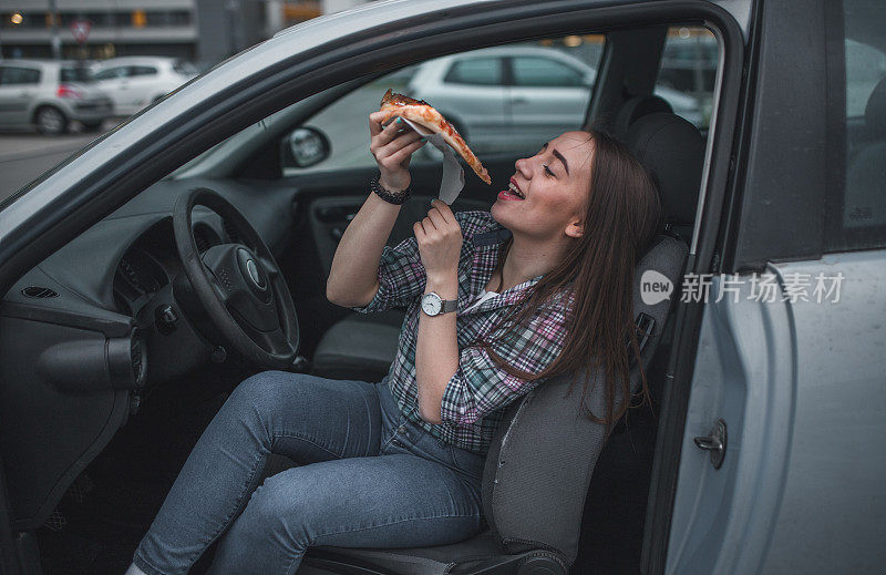 可爱的女人在停车场吃披萨