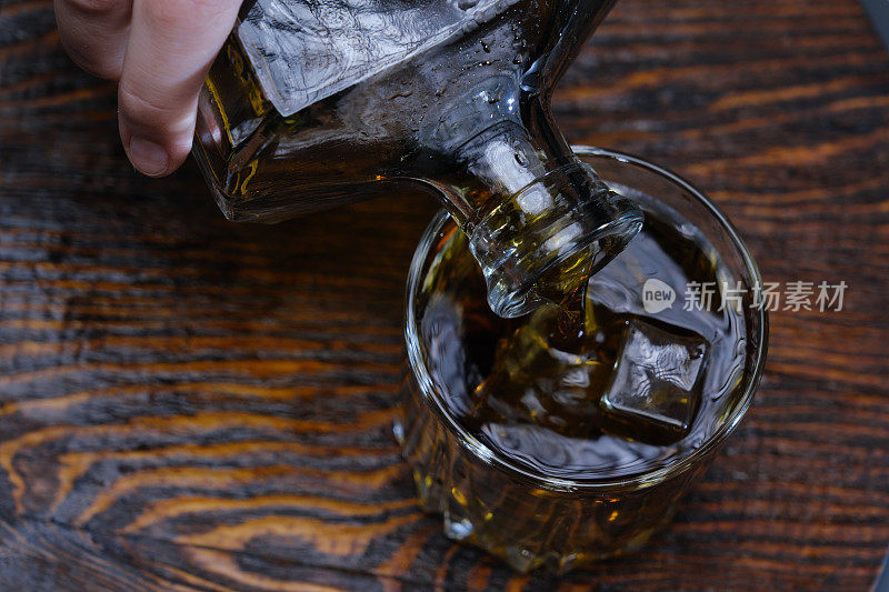 将威士忌倒入棕色木头上的玻璃杯中