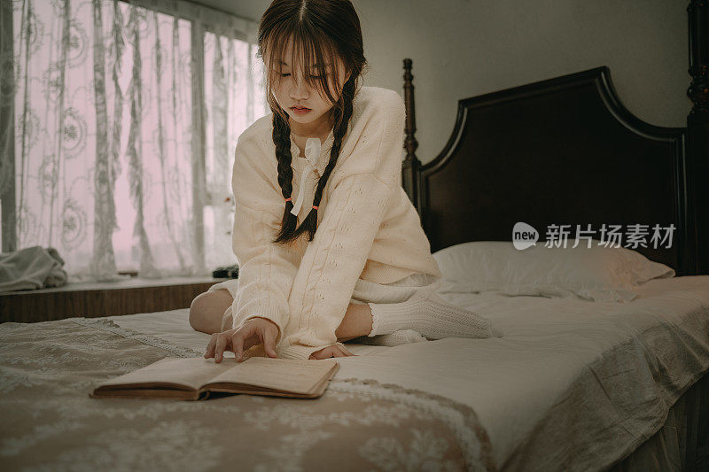 一个美丽的亚洲女孩在床上看书