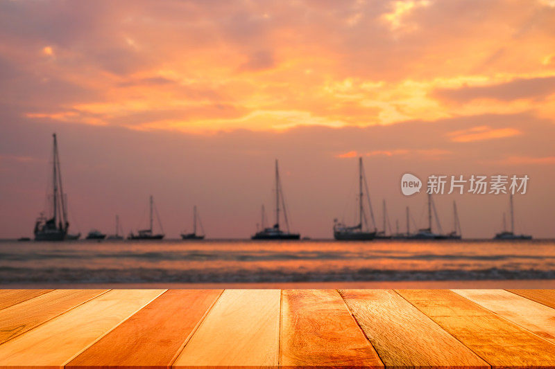 木板与模糊的帆船和日落在奈汉海滩，普吉岛，泰国。