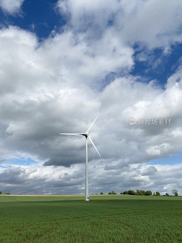 在阳光明媚和刮风的日子里，绿色田野里的风力涡轮机