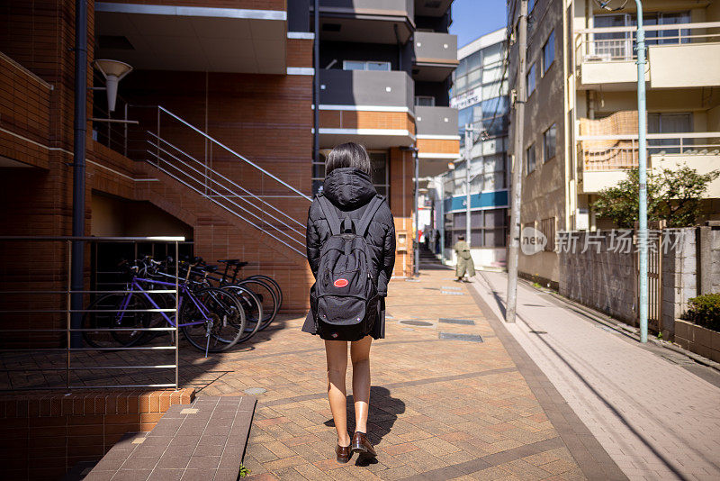 一个女学生走路回家的后视图