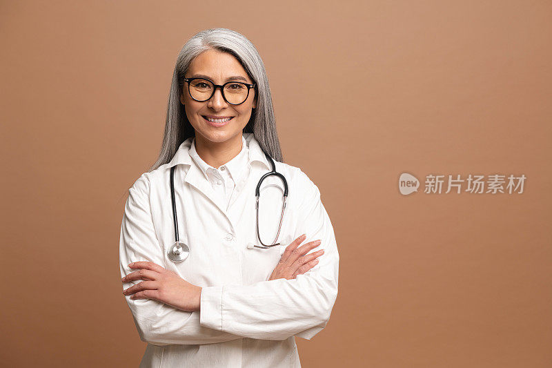 微笑着白发苍苍的亚洲女儿科医生，理疗师，穿着白色的医袍