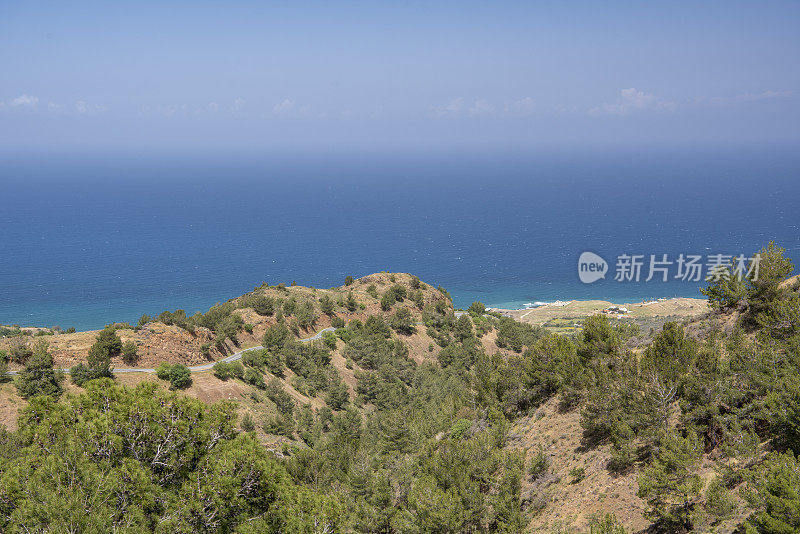 植被稀少的火山山坡，蜿蜒的道路通往海边的村庄