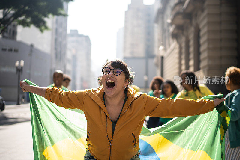 年轻女子举着巴西国旗在户外庆祝