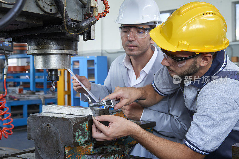 工人在工厂测量金属零件