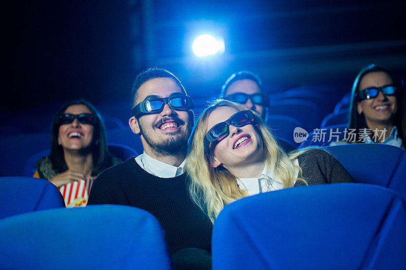 一对年轻夫妇在电影院看有趣的电影