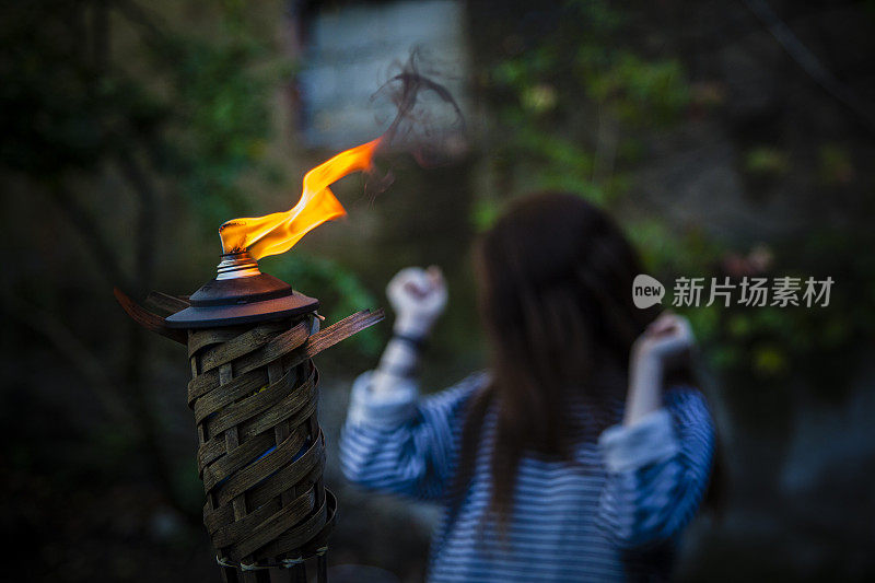 一个少女在花园里举着燃烧的火炬