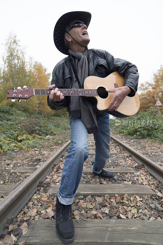 高级乡村吉他手在铁路上唱歌