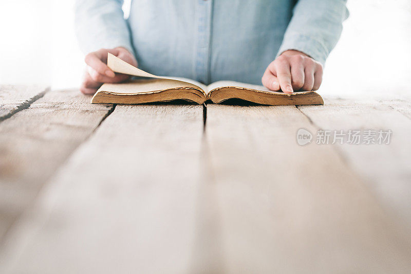 手拿圣经放在木桌上祈祷