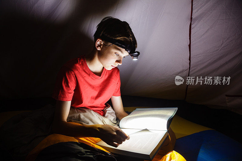 男孩在晚上用手电筒看书