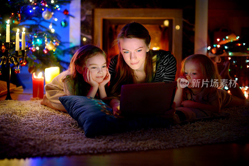 母亲和女儿在圣诞节壁炉旁使用平板电脑