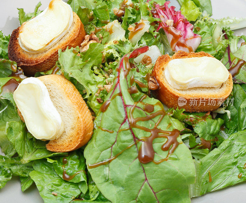 绿色沙拉，山羊奶酪和面包在盘子里