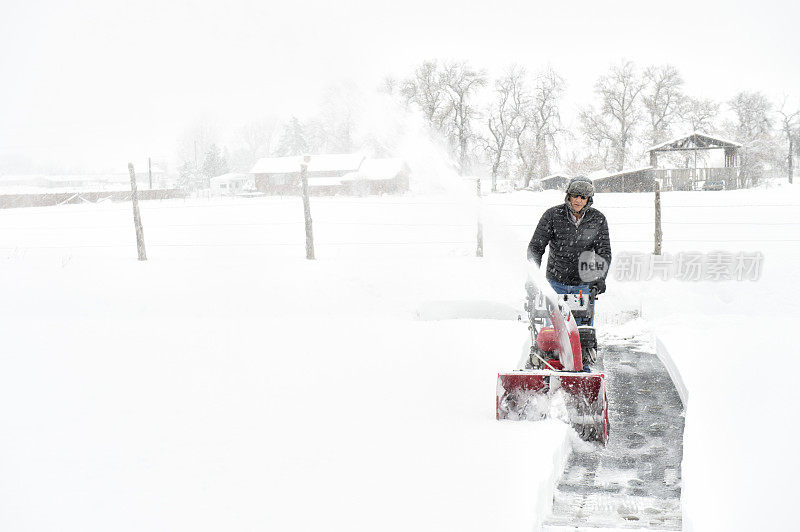 男人用他的吹雪机清理他的车道