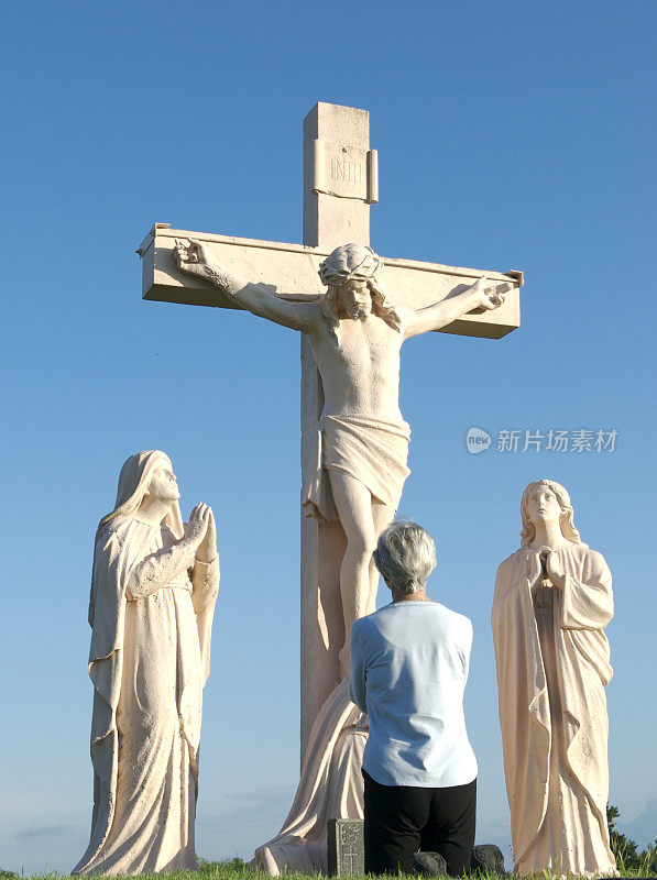 在十字架前祈祷的女士