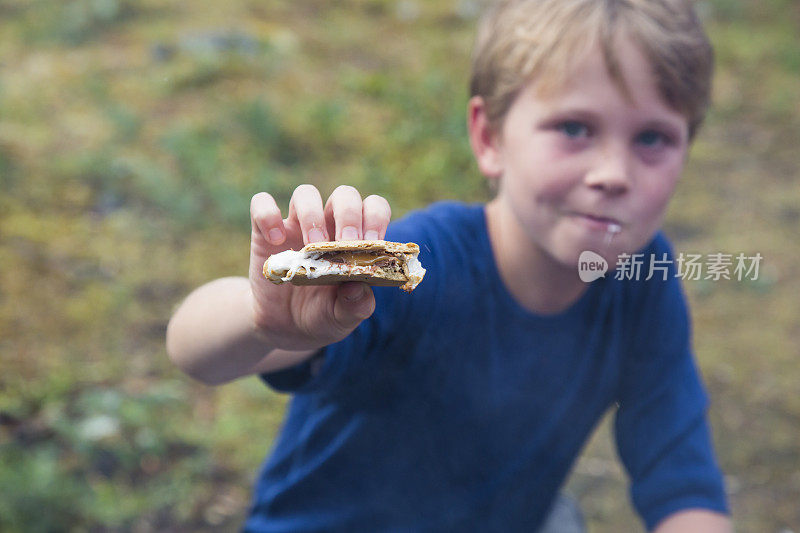 小男孩一边捏着棉花糖，一边看着镜头