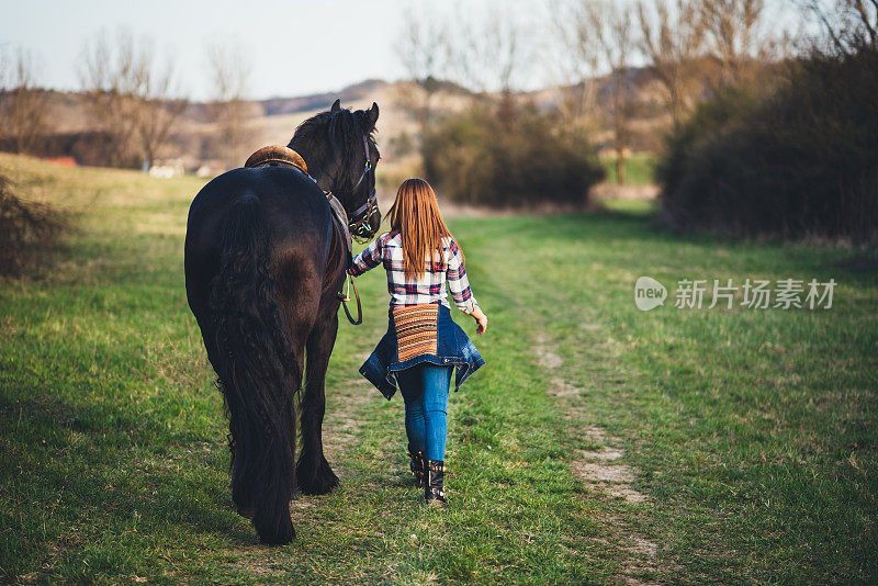 年轻女子与马散步