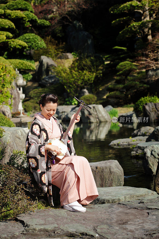 在日本花园里玩三味线的女人