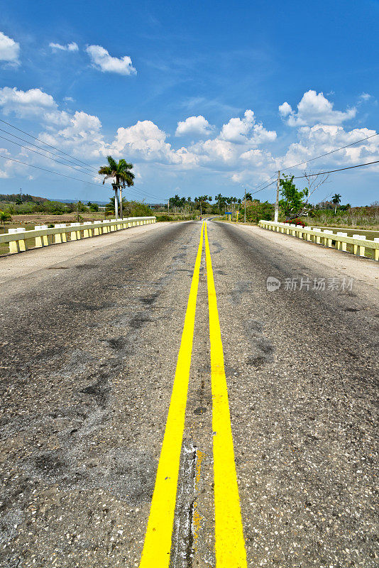 古巴的乡村公路，田野和多云的天空