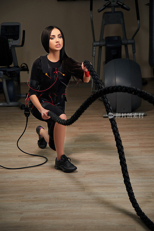 黑发女孩在EMS套装做波浪用绳子。发光效果
