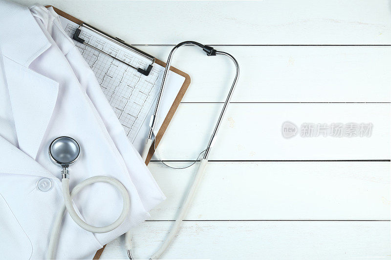 听诊器、写字板和医生制服放在整齐的白色木桌上