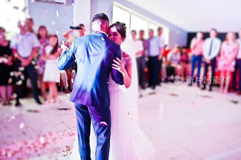 这是新人在婚礼上以五彩纸屑和彩灯为背景的感人的第一支舞。