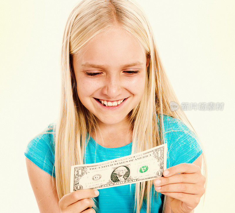 高兴的金发小女孩对着手中的美元微笑