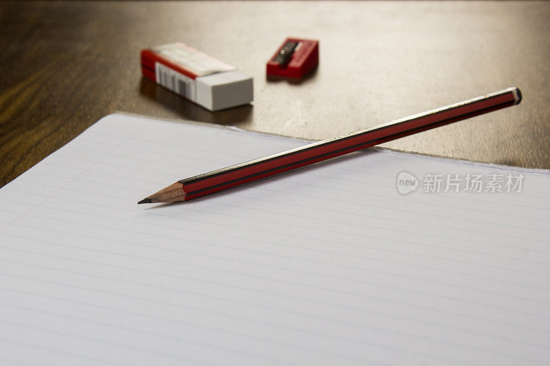 靠近一个铅笔，橡皮擦，卷笔刀和一个空白的笔记本