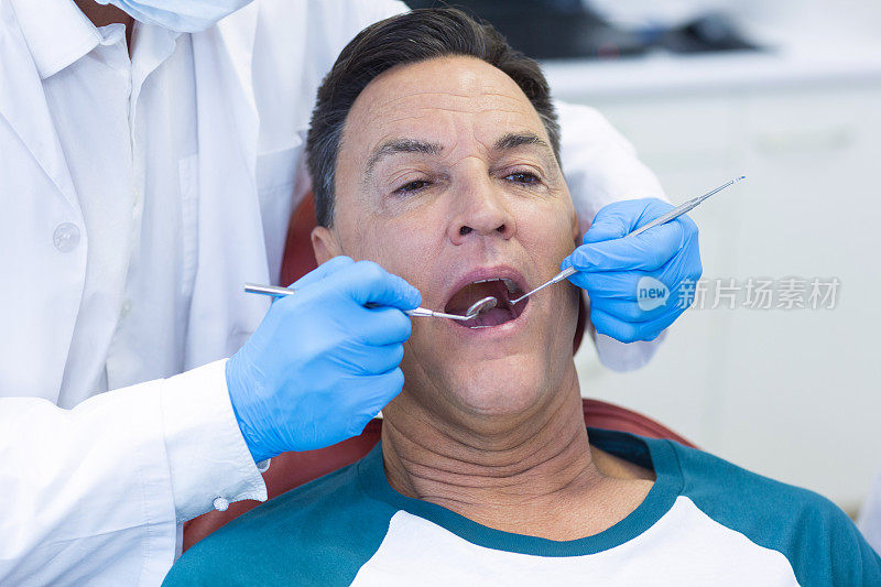牙医正在用工具检查一位男性病人