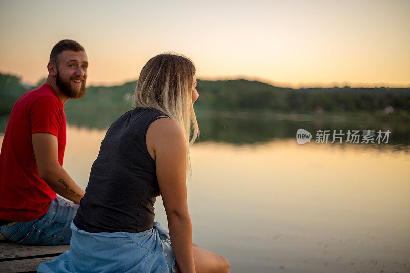 一对年轻夫妇坐在码头上