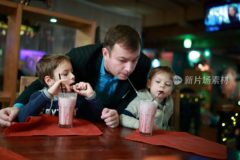 父亲和两个儿子喝着奶昔