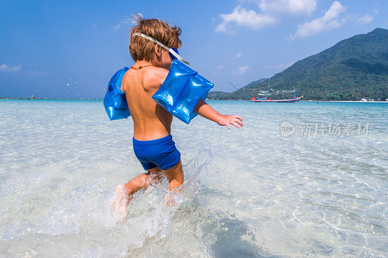 一个顽皮的小男孩在夏天的海里冲进水里。
