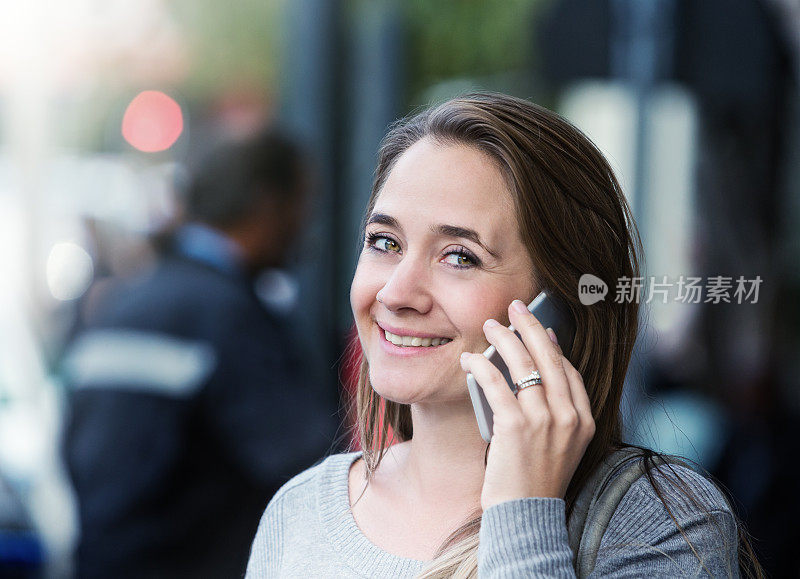 用手机说话的漂亮女人对着镜头微笑