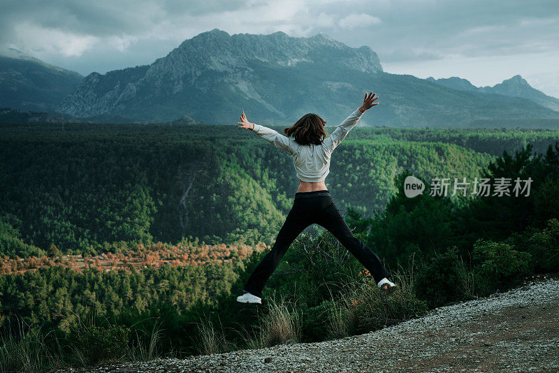 年轻的女性跑步者在晨跑前热身森林小径