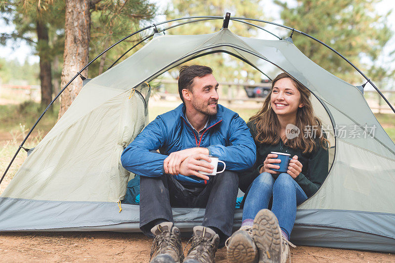 这对千禧一代夫妇在露营旅行中坐在帐篷里喝咖啡