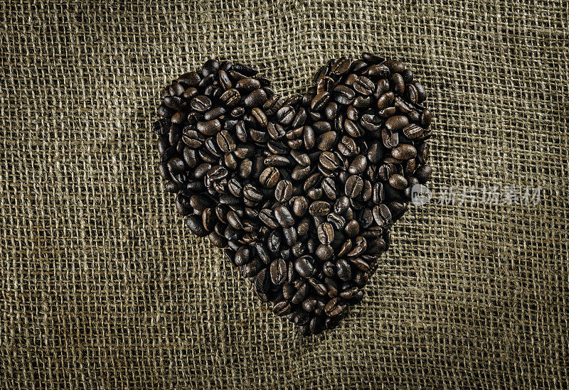 烤生的咖啡豆，在黄麻背景上做一个心形的复制空间