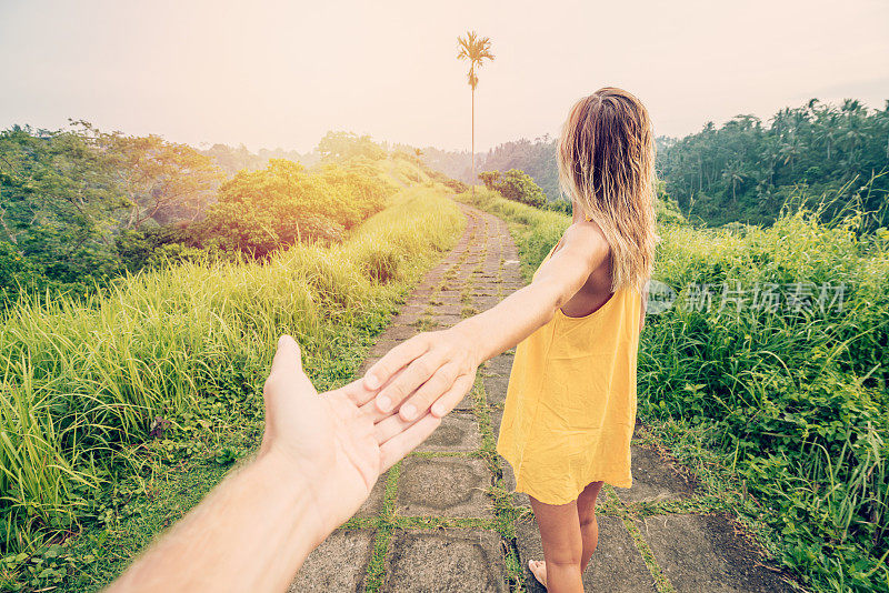 跟随我的概念年轻女子带领男友到稻田在Campuhan岭漫步在巴厘岛，亚洲人旅游奇迹分享爱的概念-